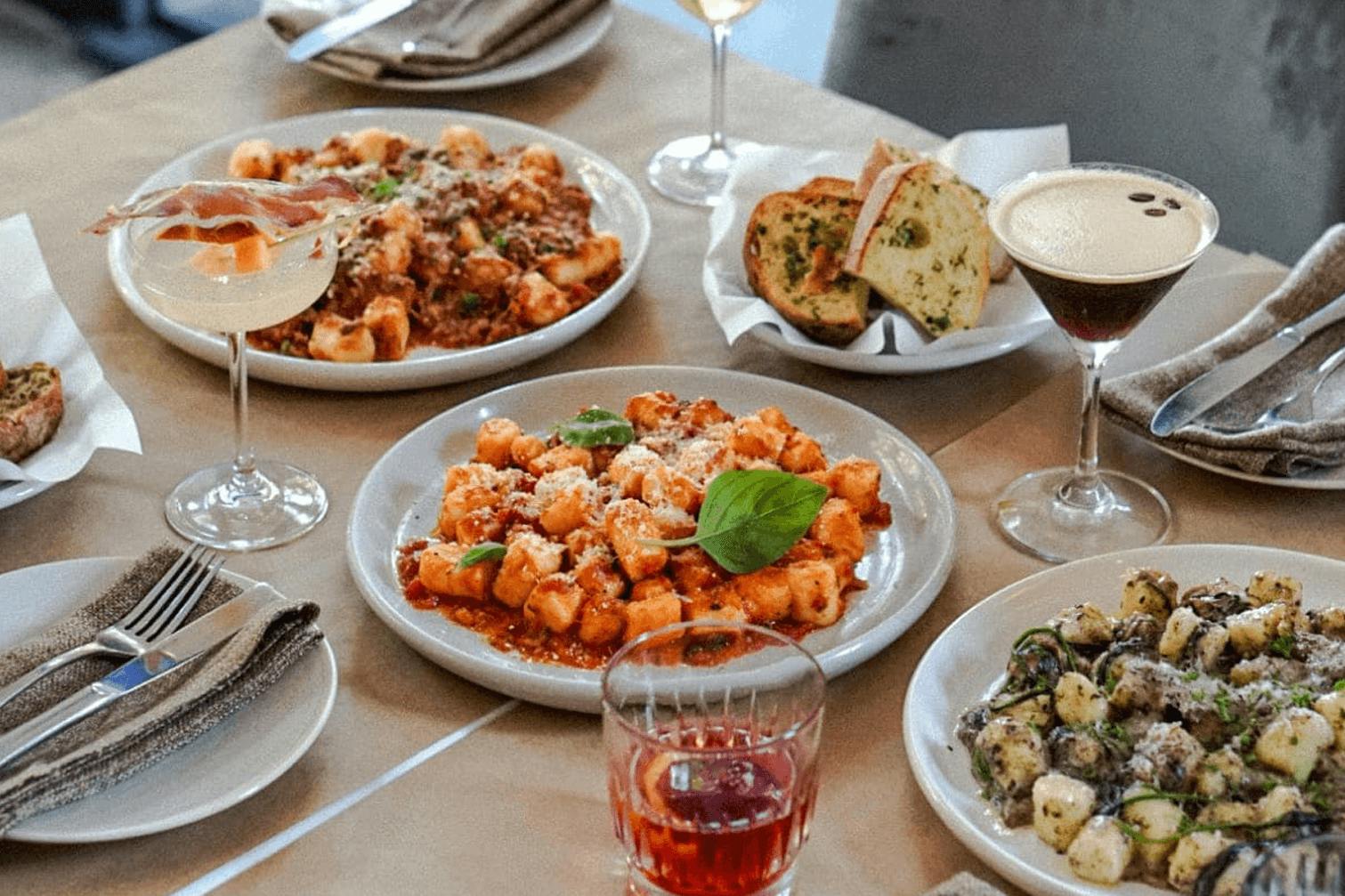 A table with three different plates of gnocchi.